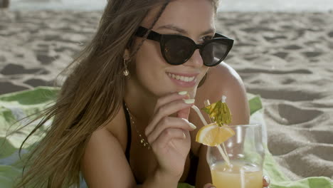 Close-up-shot-of-happy-woman-drinking-cocktail-on-sandy-beach
